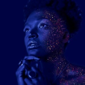 Mesmerizing portrait of a woman with glitter makeup and dramatic lighting.