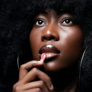 Stunning close-up of a woman with dense afro hair applying lipstick.